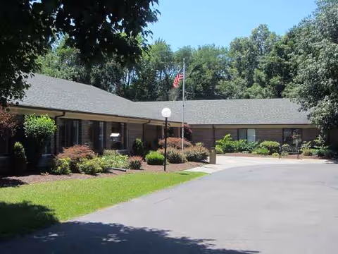 Single-story facility with landscaped entrance and flagpole in front of Wintersong Village.