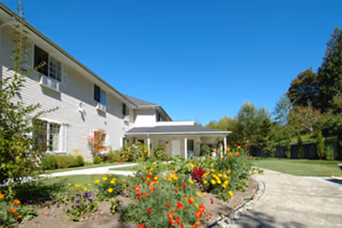 Exterior view of Cascade Valley Senior Living with a flower garden and walkway