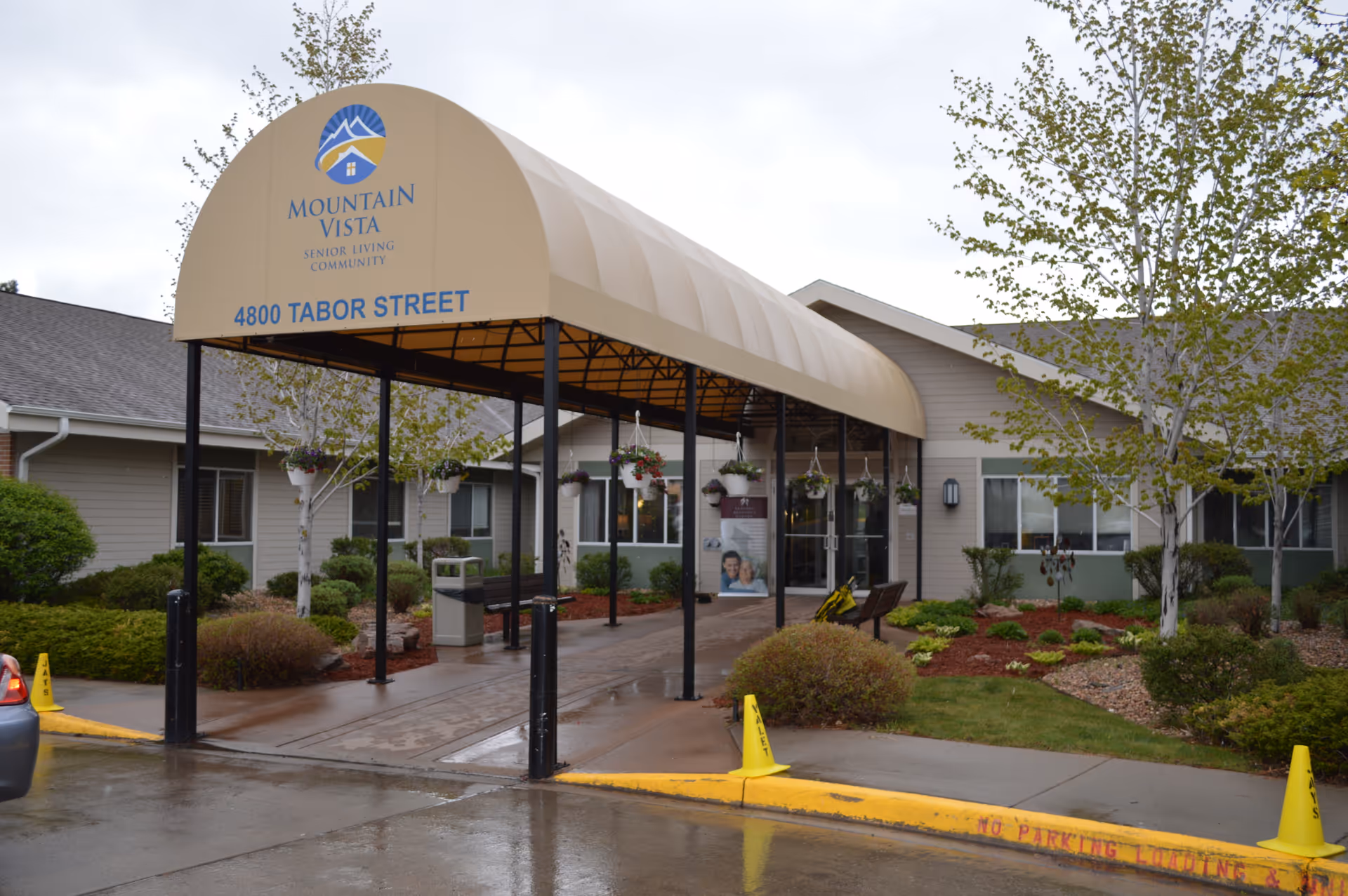 Front entrance canopy and facade of Mountain Vista Senior Living Community showing the address and landscaped grounds.