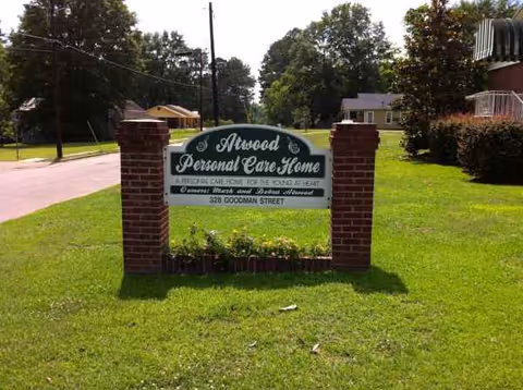 Brick-framed sign for Atwood Personal Care Home sits on a grassy front yard.