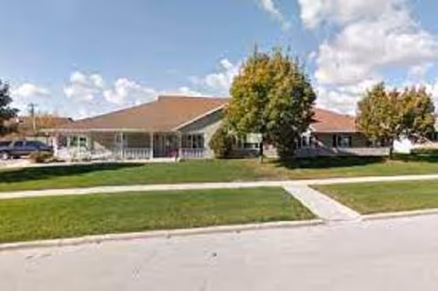 Front view of Eden Vista Fond Du Lac senior living facility with green lawn and trees.
