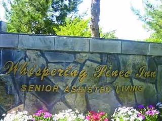 Stone wall sign reads Whispering Pines Inn, Senior Assisted Living, at the entrance.