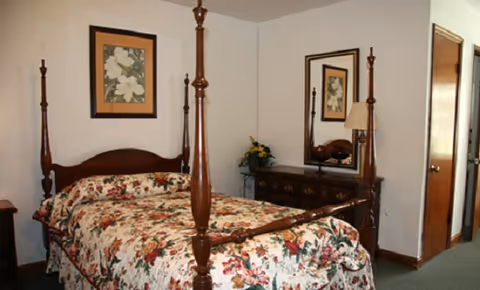 Floral four-poster bed with matching dresser and mirror fills a traditional bedroom.