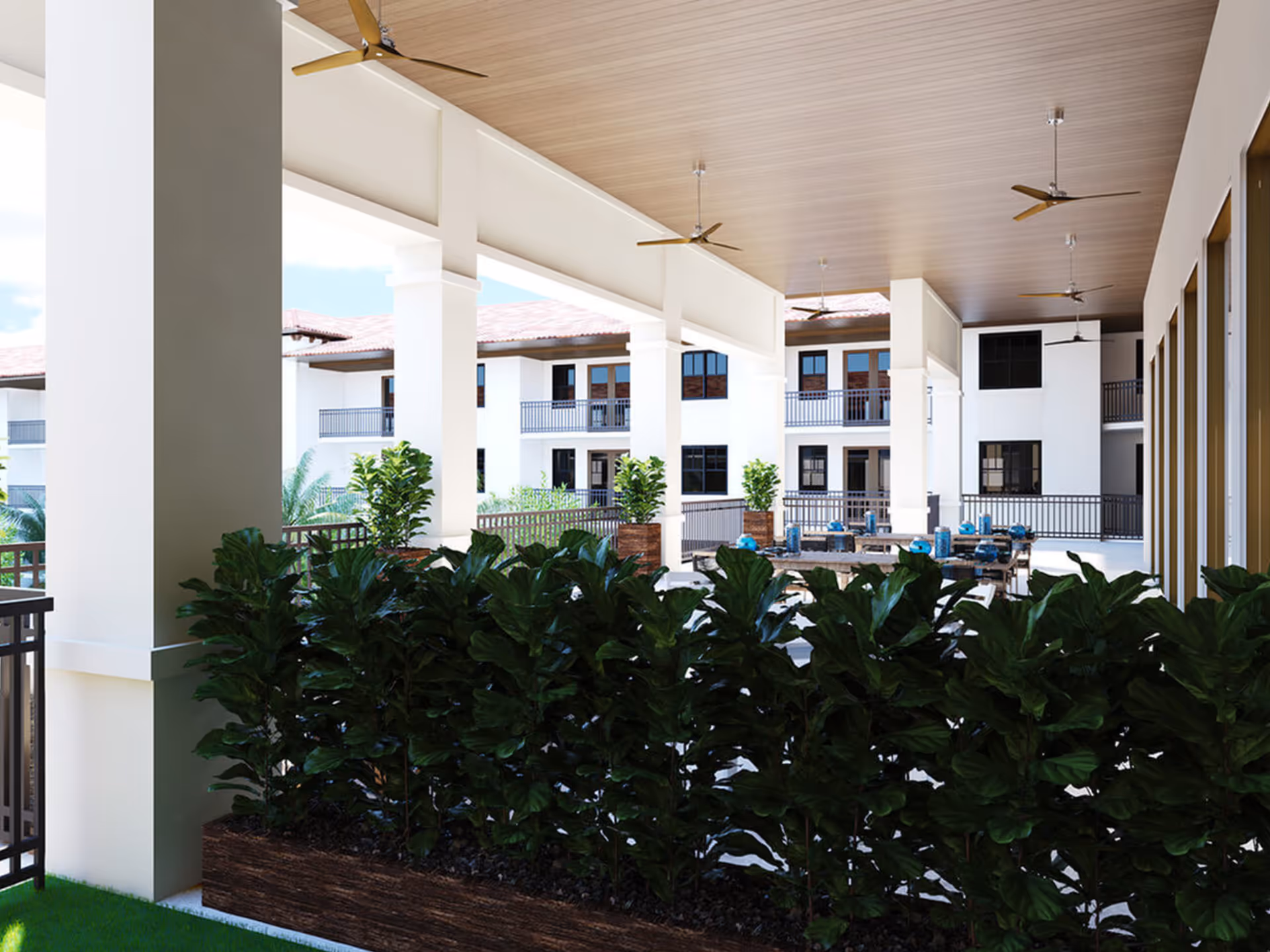 Covered outdoor courtyard seating area with potted plants, ceiling fans, and surrounding apartment balconies.