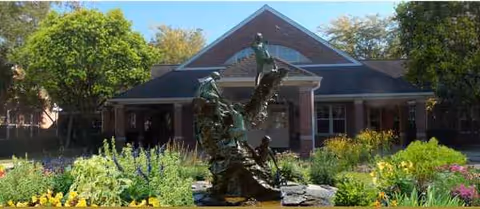 Front exterior of The Wealshire with a landscaped garden and central fountain sculpture.