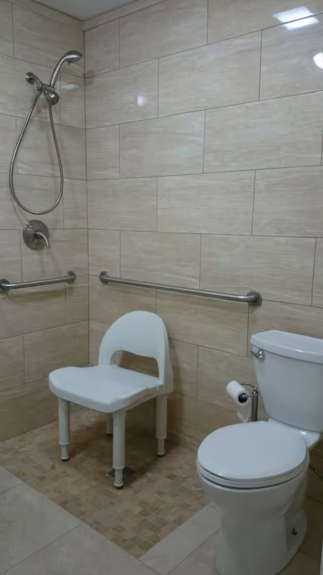 Tiled accessible bathroom with a handheld shower, a white shower chair, horizontal grab bars, and a toilet.