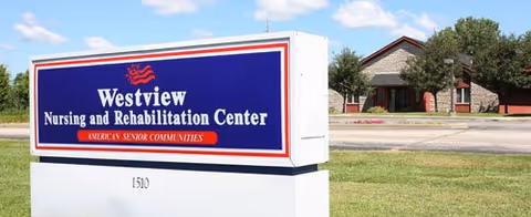 Outdoor view of Westview Nursing and Rehabilitation Center sign with the building and trees in the background under a clear sky.