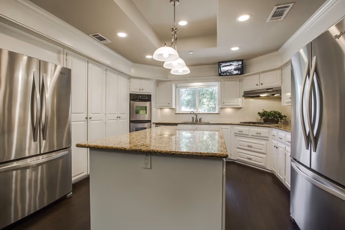 Bright modern kitchen with a central island, granite countertops, white cabinetry, and stainless steel French-door refrigerators.