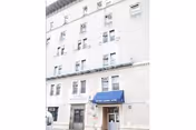 Exterior view of a multi-story beige brick building with several windows and a blue awning above the entrance that reads 'Oxford Nursing Home'.