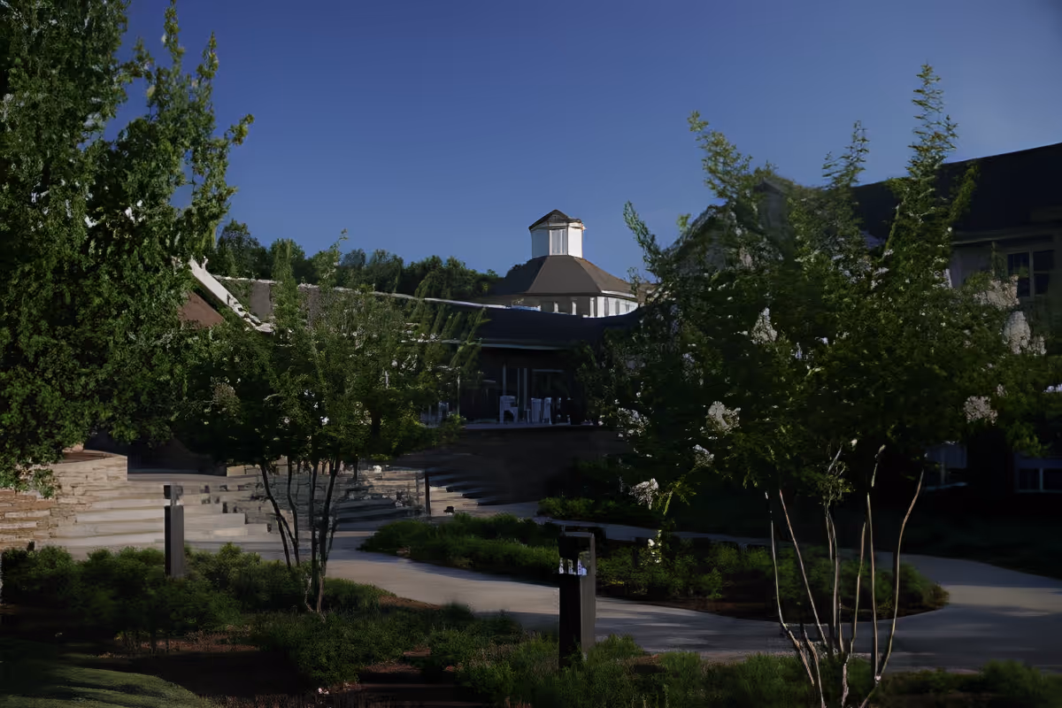 Exterior view of The Haven at Regency Pointe showing a landscaped courtyard with walkways and stairs leading to the facility's multi-story building topped by a cupola.