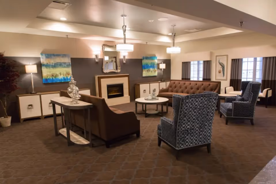 Spacious communal lounge with sofas, armchairs, a fireplace, coffee tables, and wall artwork.