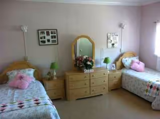Symmetrical twin bedroom with two beds, dressers, lamps, a mirror, and a flower bouquet.