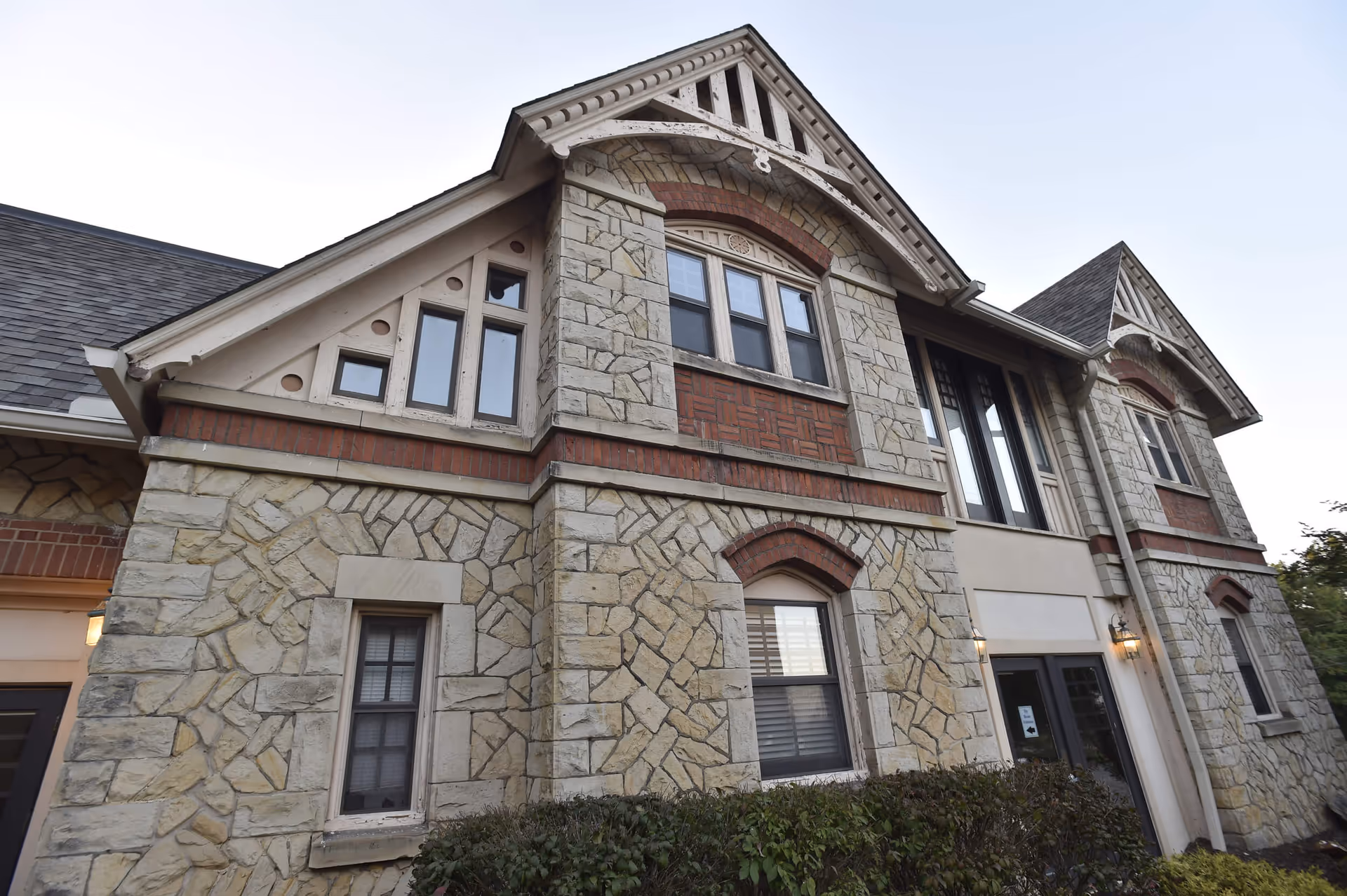 Two-story stone-and-brick building facade with decorative gables and multiple windows.