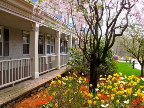 Grove Manor Estates exterior with a covered porch and blooming flower garden.