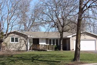 Front view of a single-story senior living facility with a porch and bare trees.