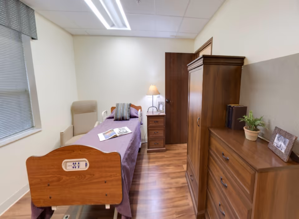 Private resident bedroom with a single bed, nightstand, armchair, wardrobe and dresser.