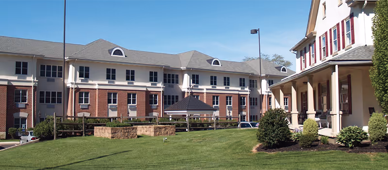 Exterior view of Sacred Heart Senior Living campus with lawn, courtyard, and clubhouse.