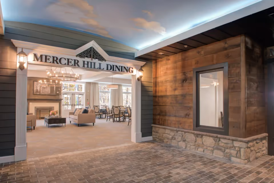 Entrance to Mercer Hill Dining showing a furnished dining and lounge area with a fireplace and chandelier.