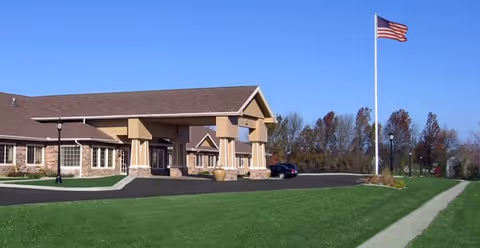 Front exterior view of Amber Glen Memory Care building with entrance and flagpole.