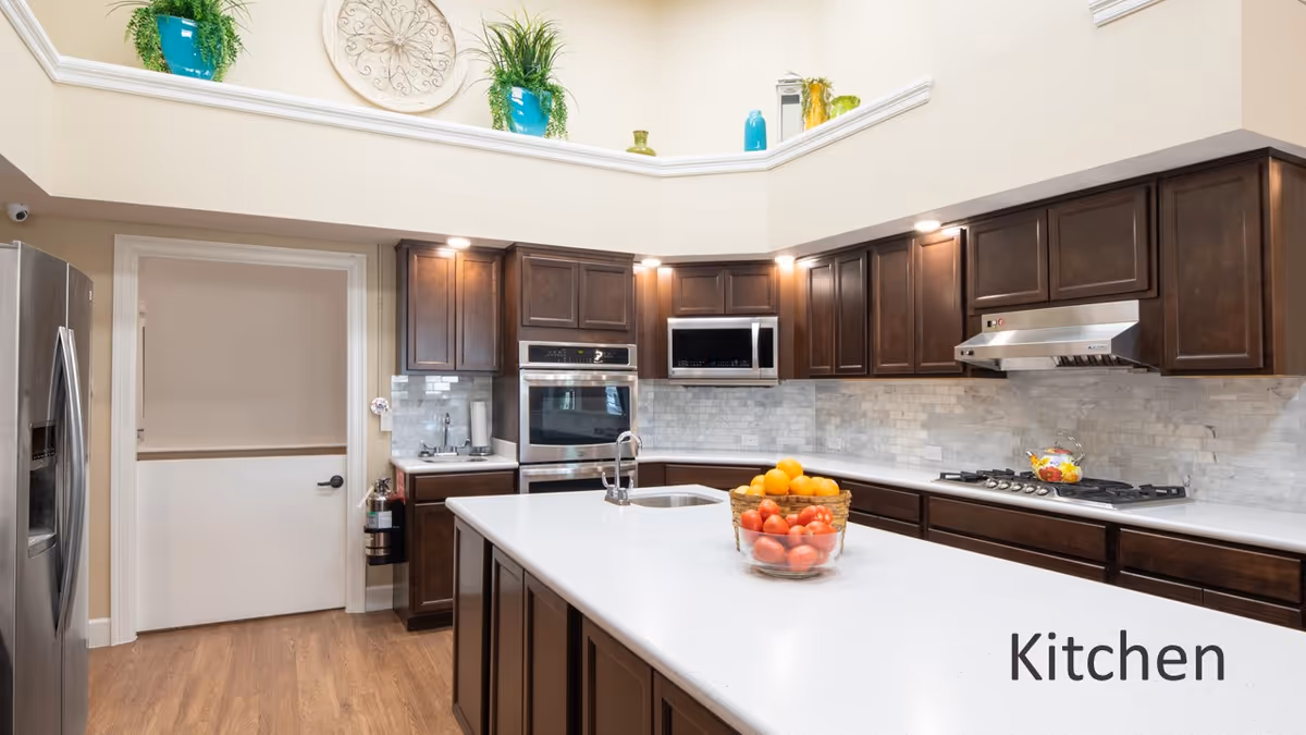 Bright modern kitchen with a large white island, dark wood cabinets, stainless steel appliances, and a bowl of fruit on the counter.