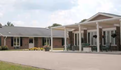 Brick senior living facility with a covered entrance and outdoor seating.