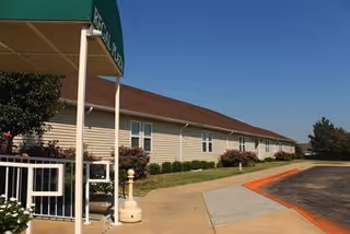 Exterior view of Regal Plaza senior living facility front with sign, walkway, and landscaping.