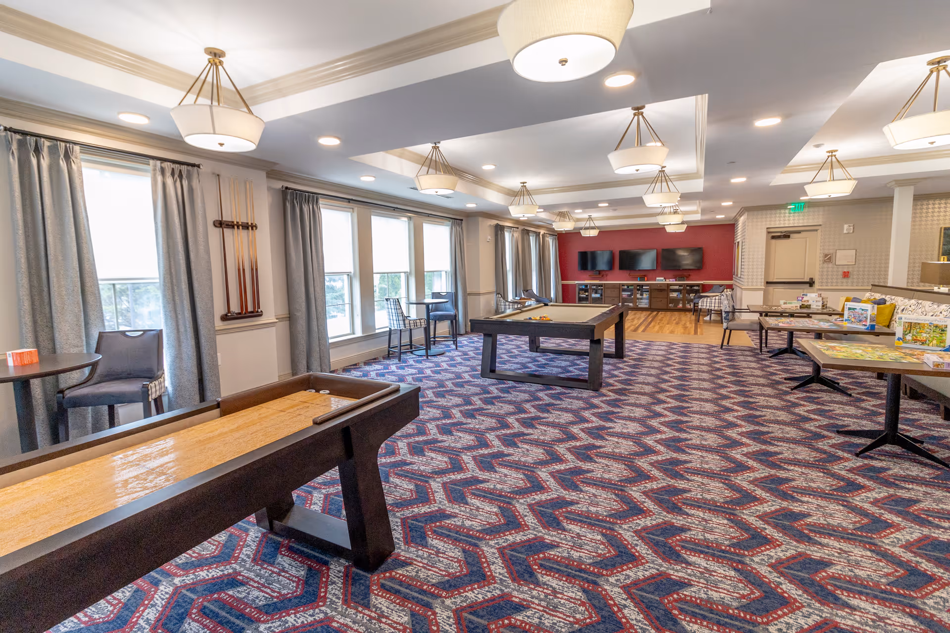 Spacious senior living common area with game tables, seating, and large windows.