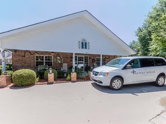 Exterior of Alpine House senior living facility with a white van in front.
