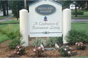 A sign for Hugh Ash Manor retirement living sits among landscaped flowers.