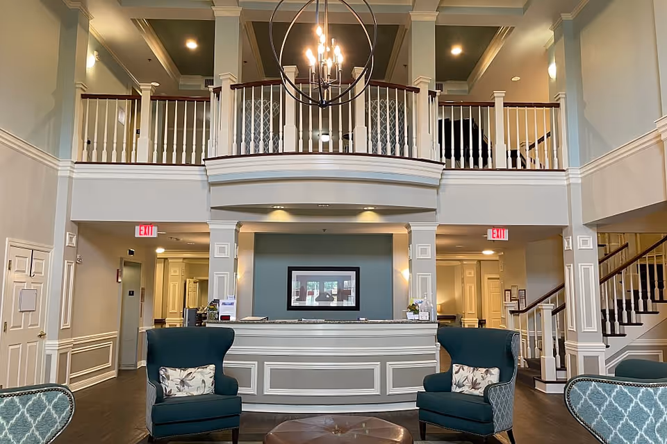 Interior view of the lobby at The Rutherford Assisted Living, featuring a reception desk, comfortable seating, and a staircase leading to the upper level.