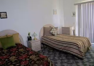 Two single beds with nightstands and a dresser in a shared bedroom.