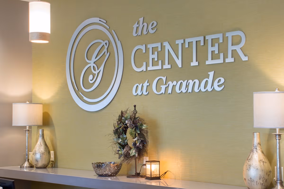 Reception wall displaying 'the CENTER at Grande' signage with lamps, decorative wreath, and countertop accents.