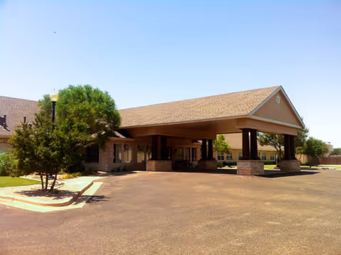 Single-story senior living building entrance with a covered porte-cochère and paved driveway.