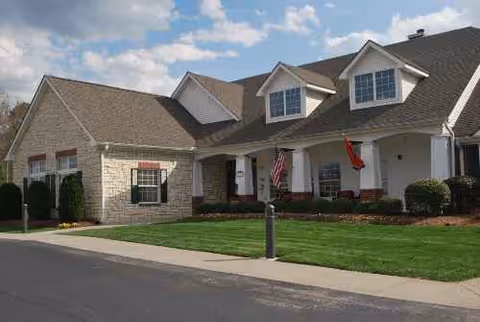 Exterior view of a senior living facility with a manicured lawn and entryway.