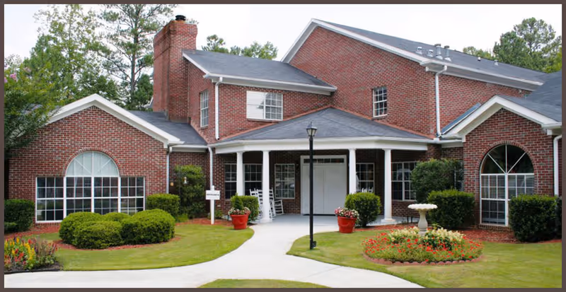 Brick senior living facility with a covered entrance and landscaped front yard.