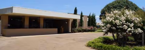 Front view of a single-story nursing home entrance with a driveway and landscaping.