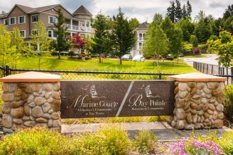 Stone entrance gate with Marine Courte Bay Pointe memory care sign and green landscape behind