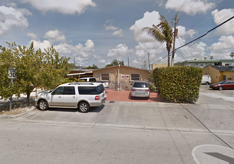 Street view of a small beige senior facility with parked cars in front