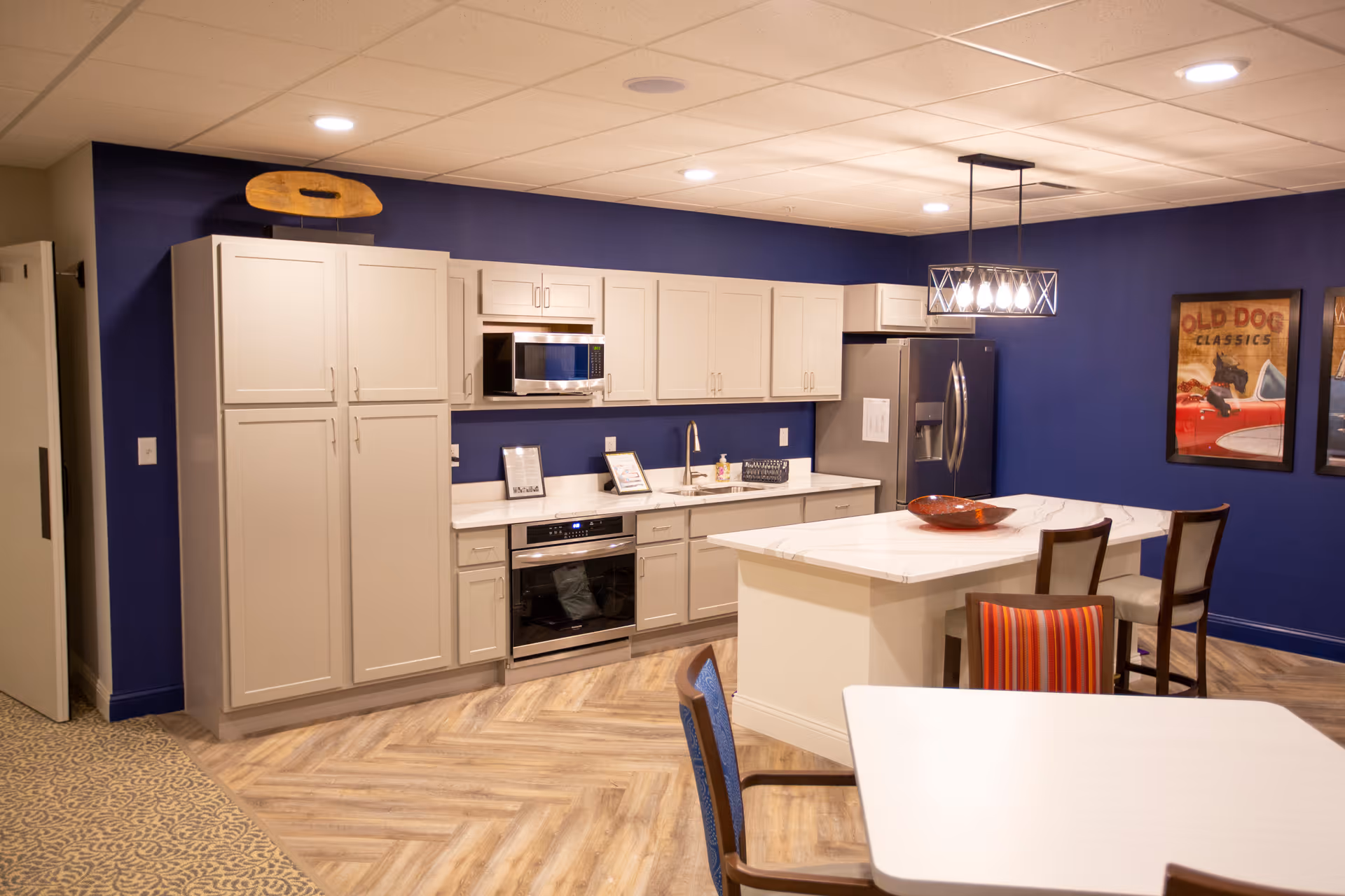Open kitchen and dining area with navy blue walls, white cabinets, a central island, and seating.