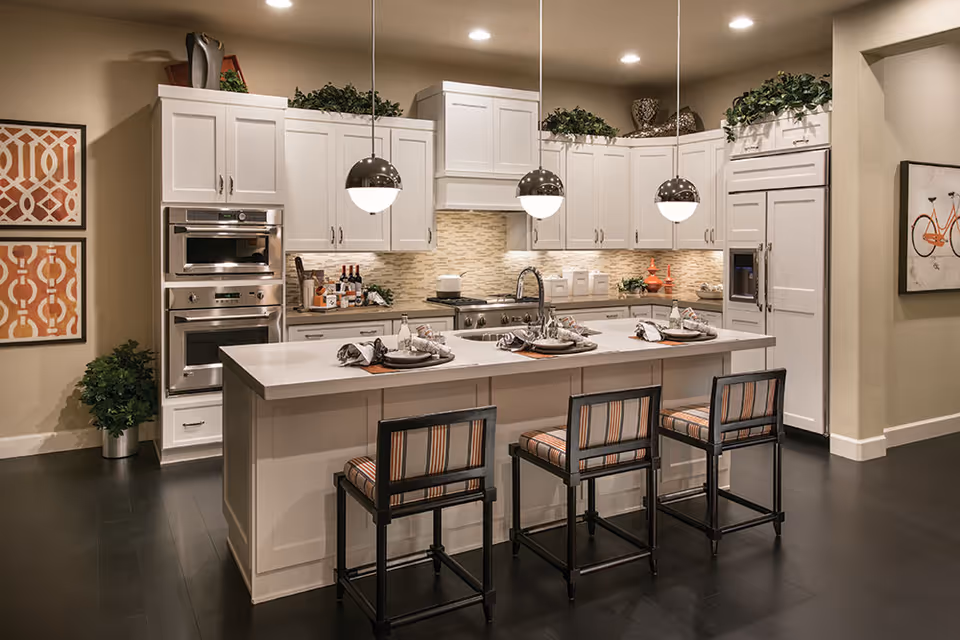 Bright modern kitchen with white cabinetry, a large island set with three bar stools and pendant lights.