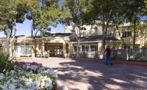 Exterior view of Newark Gardens I senior living facility entrance with trees and flowers.