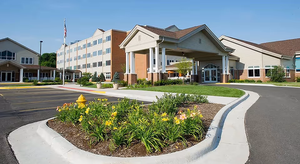 Exterior view of Pleasant View Hearthstone Al facility with driveway, entrance canopy, and landscaped flower beds.
