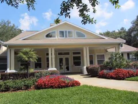 Sunny front entrance of Pennbrooke Fairways, with columns, greenery, and a manicured lawn.