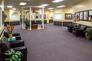 Indoor lobby of Marquis Vermont Hills with seating, plants, framed artwork, and a central pillar.