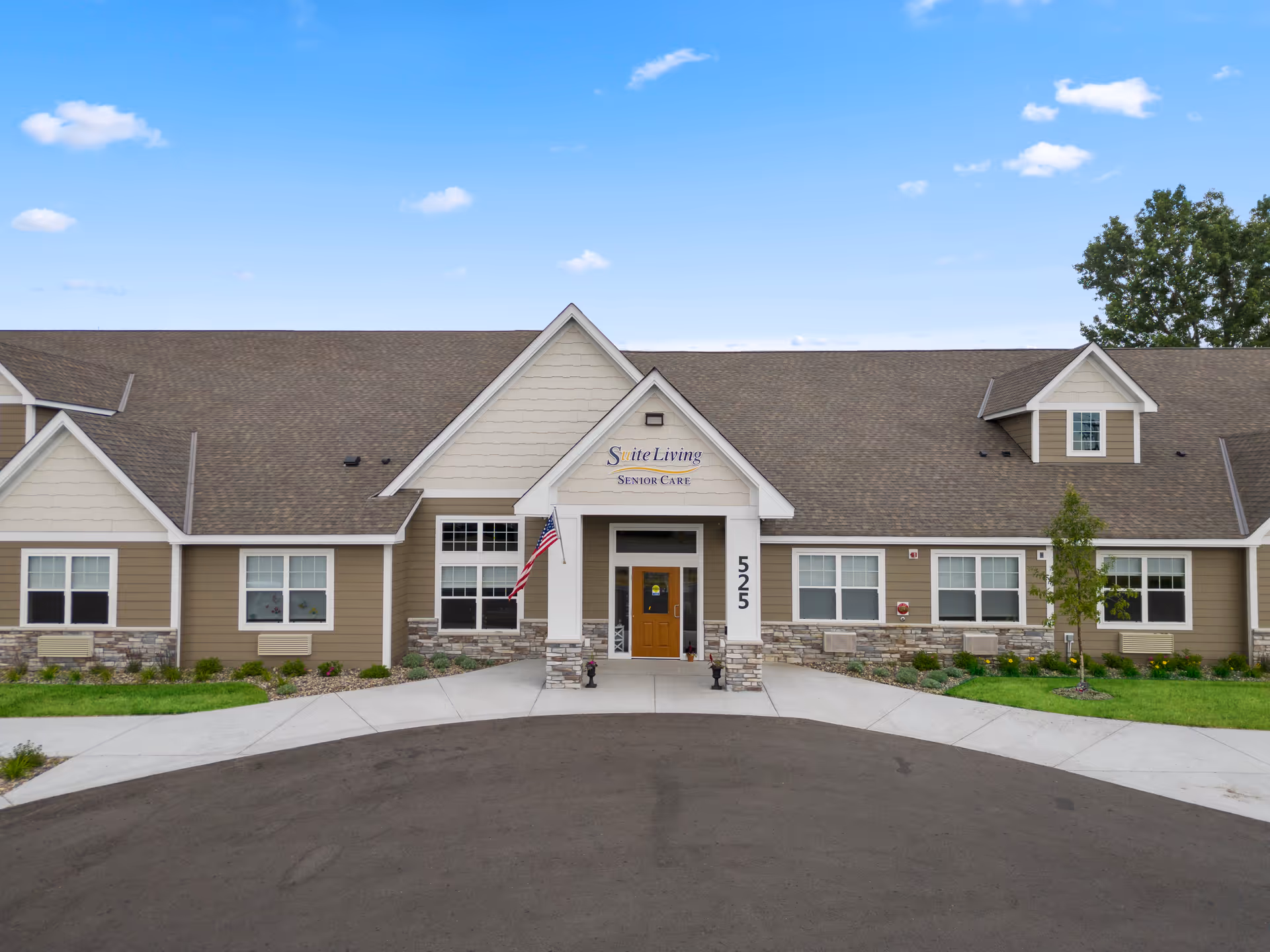 Front exterior of the Suite Living senior care building showing the central entrance, American flag, and address number 525.