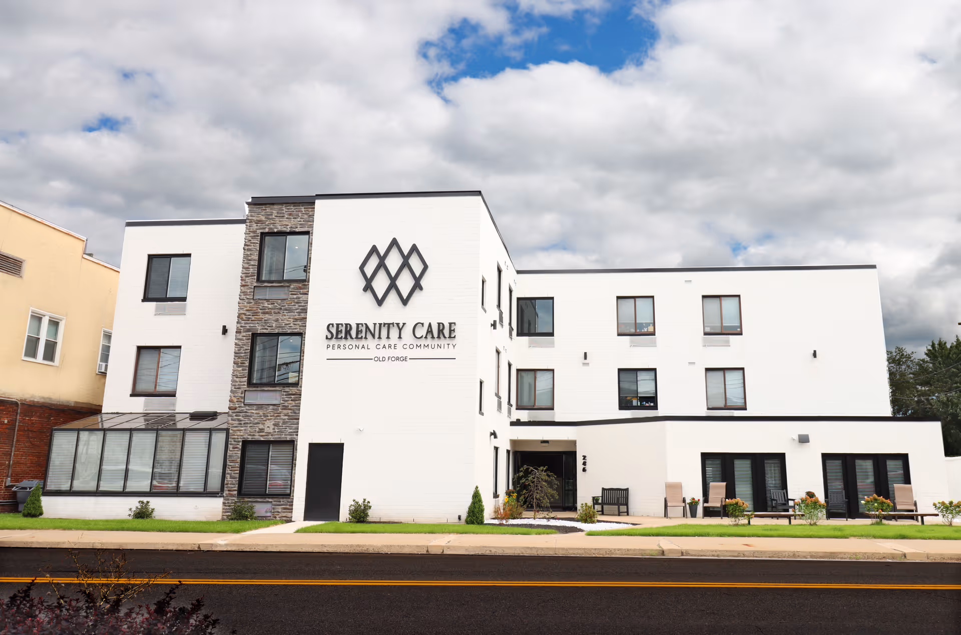 Front exterior of the three-story Serenity Care personal care community building with its sign, windows, and entrance.