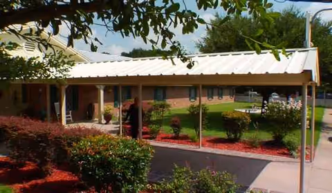 Exterior view of Madisonville Assisted Living with a covered walkway, brick building, and landscaped front yard.