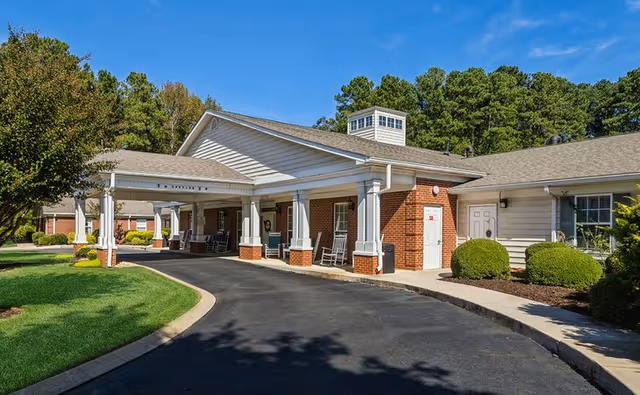Exterior view of a senior living facility with a covered entrance and brick columns.