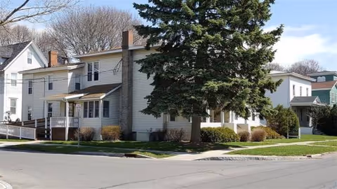 Exterior view of a senior living facility building along a tree-lined street.