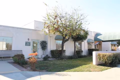 Front exterior of Mission de la Casa Nursing and Rehabilitation Center with trees and benches.